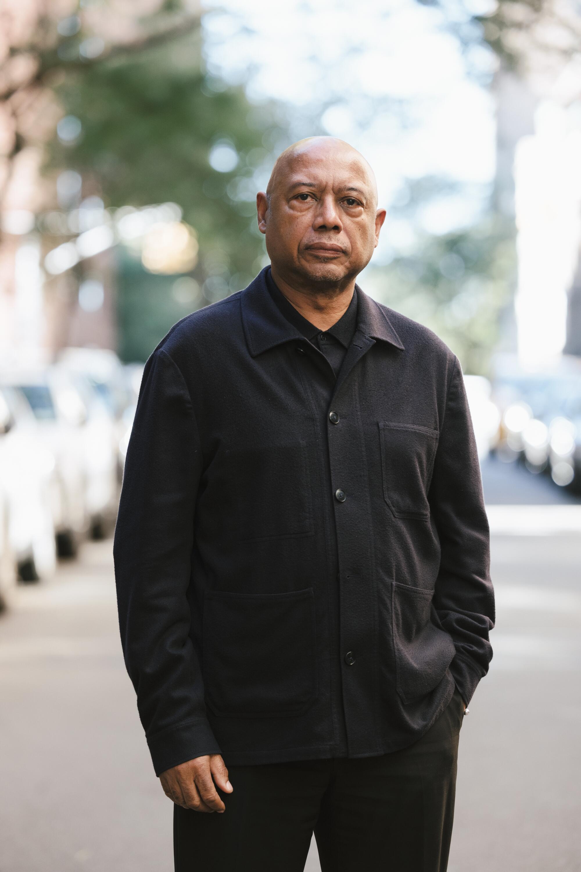 A man clad in black stands in a New York City street.