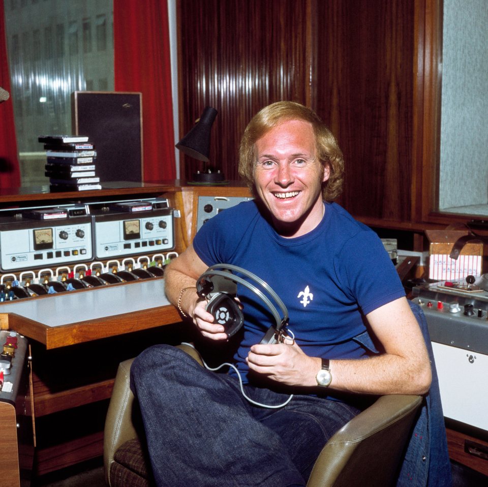 a man in a blue shirt is holding a pair of headphones