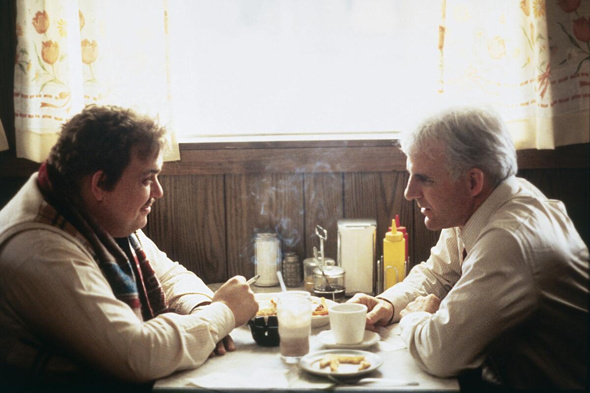 Two sitting across from one another at a diner booth.
