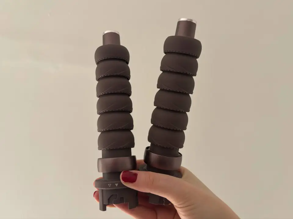 Two brown hair styling wands held in a hand.