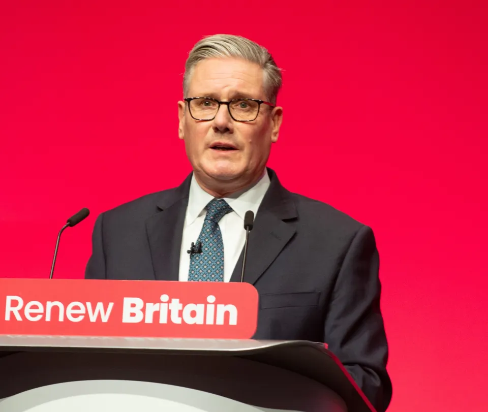 Keir Starmer at a podium with "Renew Britain" visible, speaking at the Labour Party Conference.