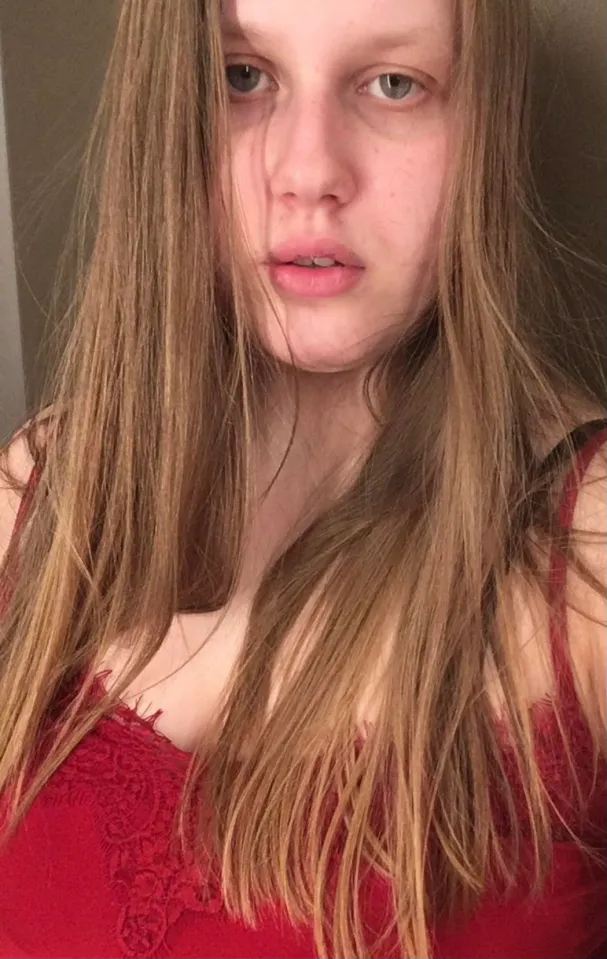 A woman with long light brown hair wearing a red top.