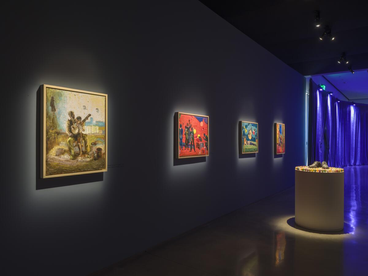 A darkened gallery featuring illuminated paitings.