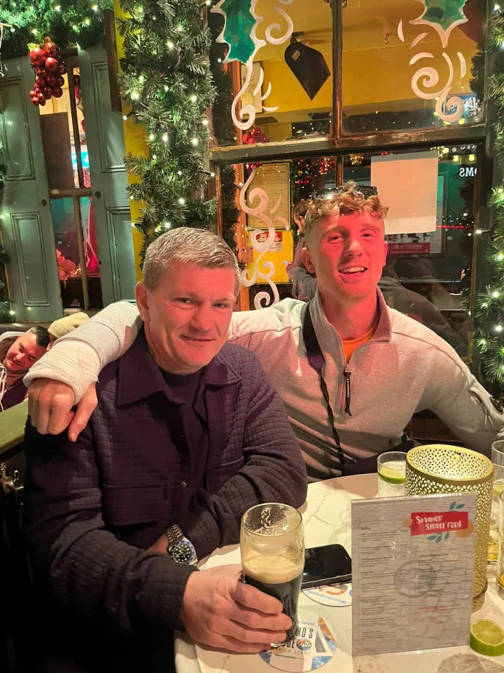 Two men sitting at a table with drinks and a menu, surrounded by Christmas decorations.