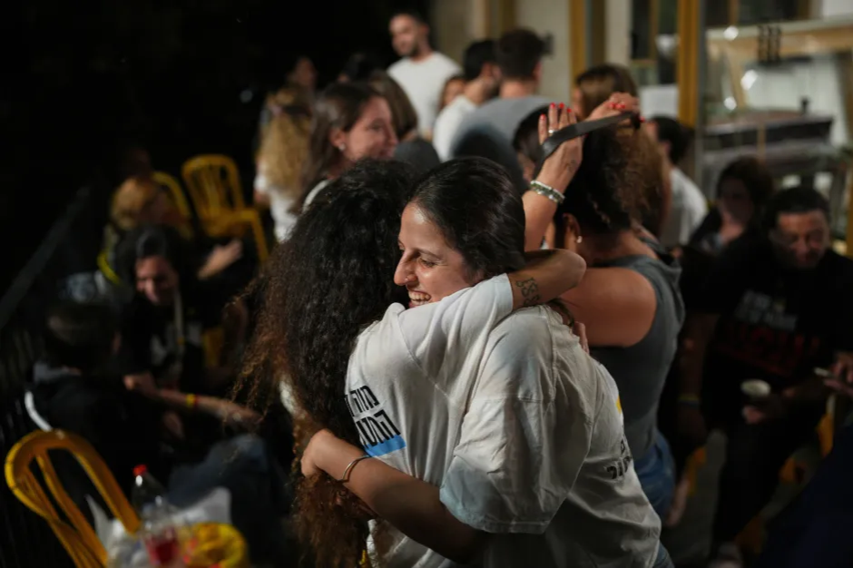 Two women embracing and smiling in a crowd.