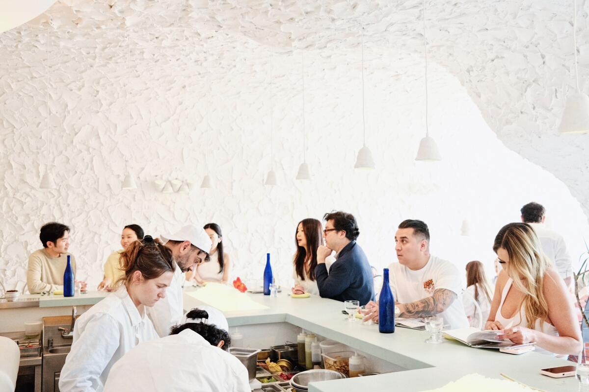 Guests sit around the bar at Cento Raw Bar, an all-white restaurant and bar
