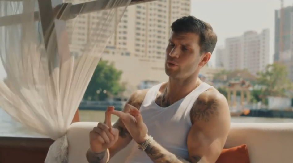 A man in a white tank top gesturing with his hands.