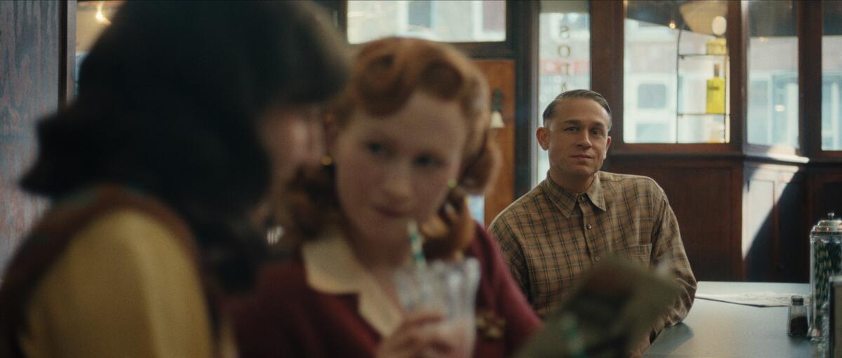 A man sits and admires two women, one of which is drinking a milkshake.