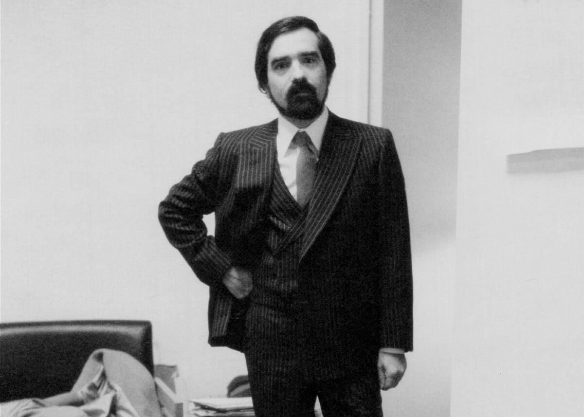 A bearded man in a dark suit poses for the camera.