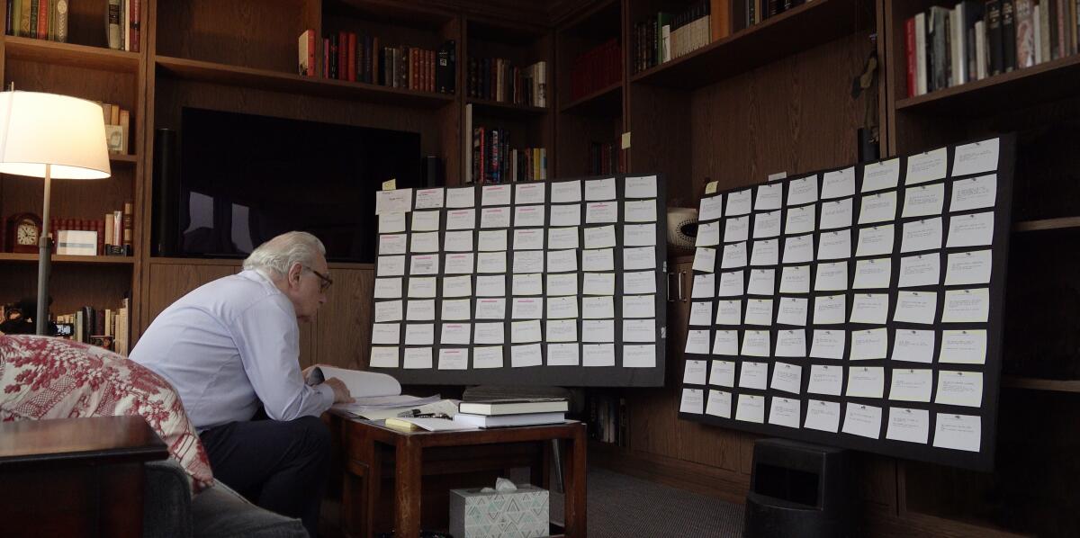 A director studies a script in front of boards of index cards.