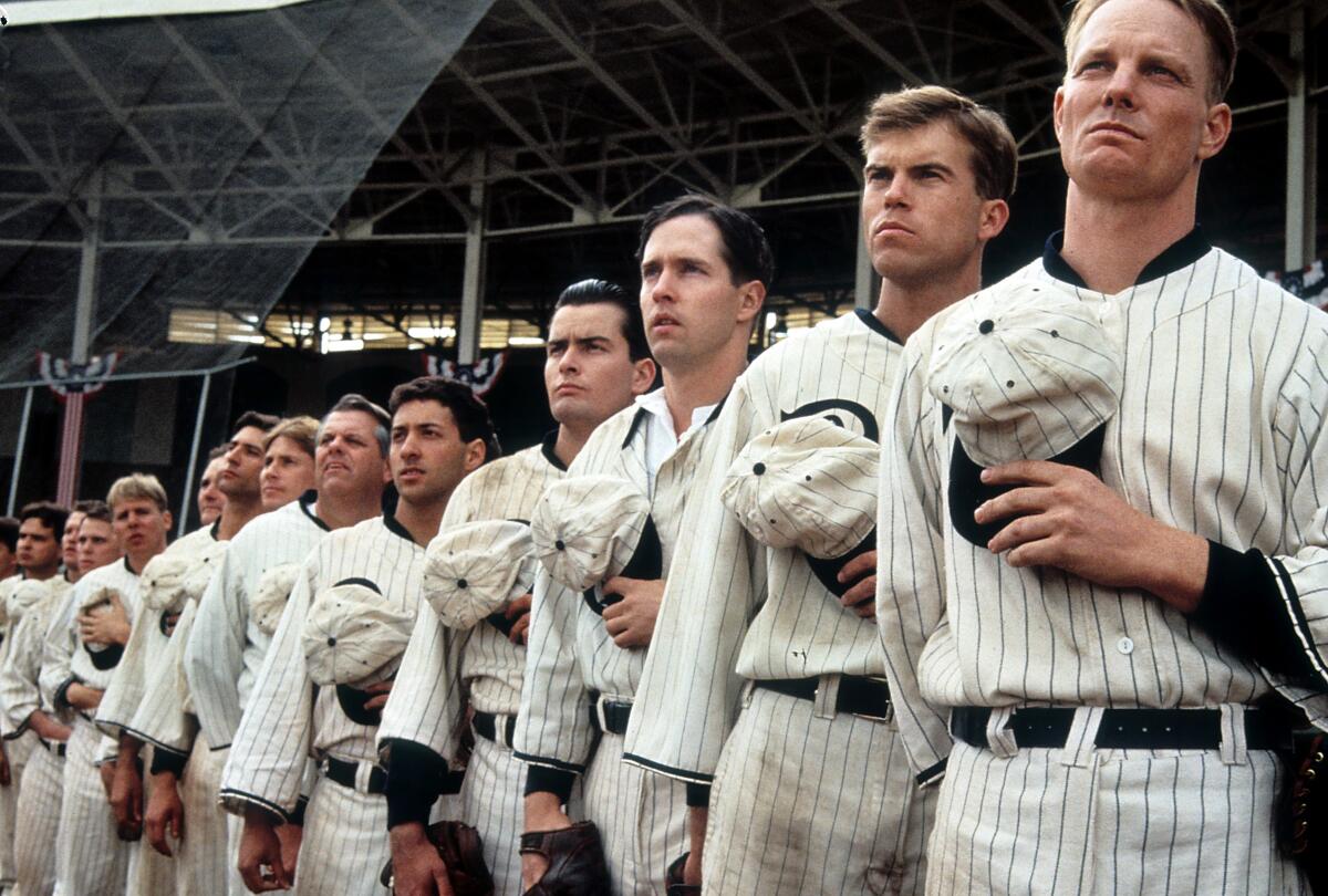 Baseball players stand for the national anthem.