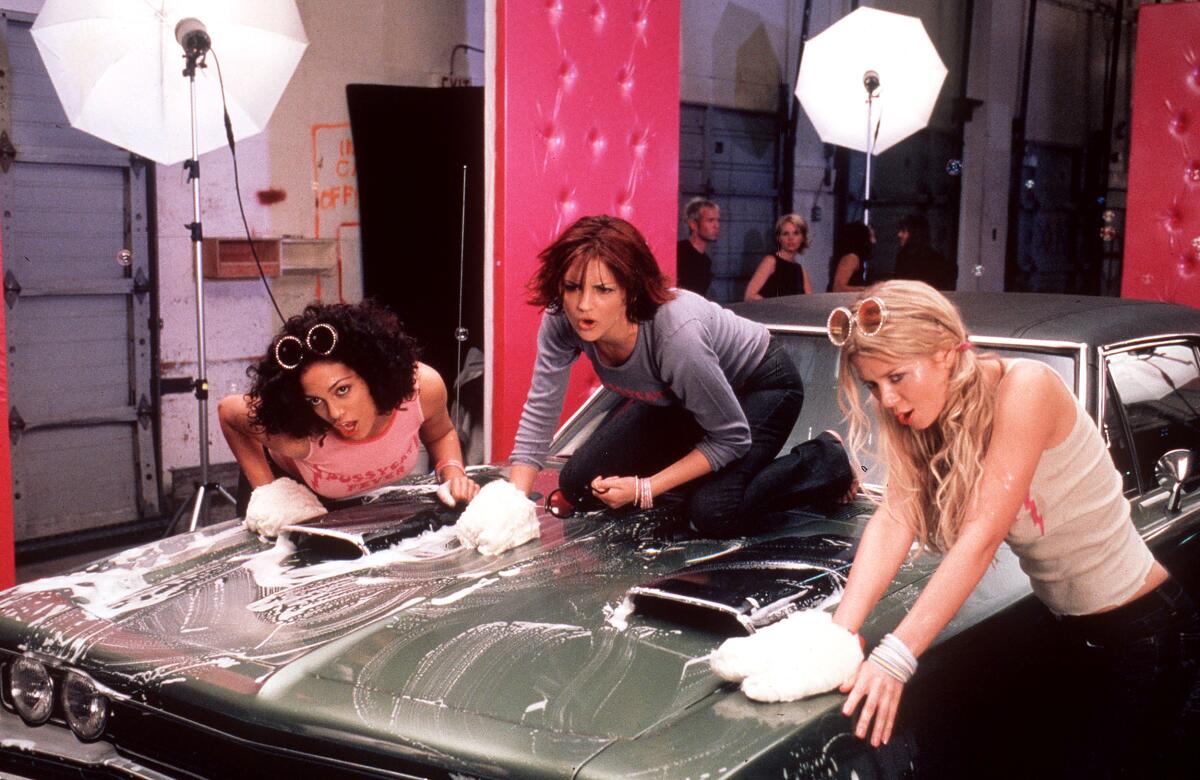 Three women wash the hood of a car.
