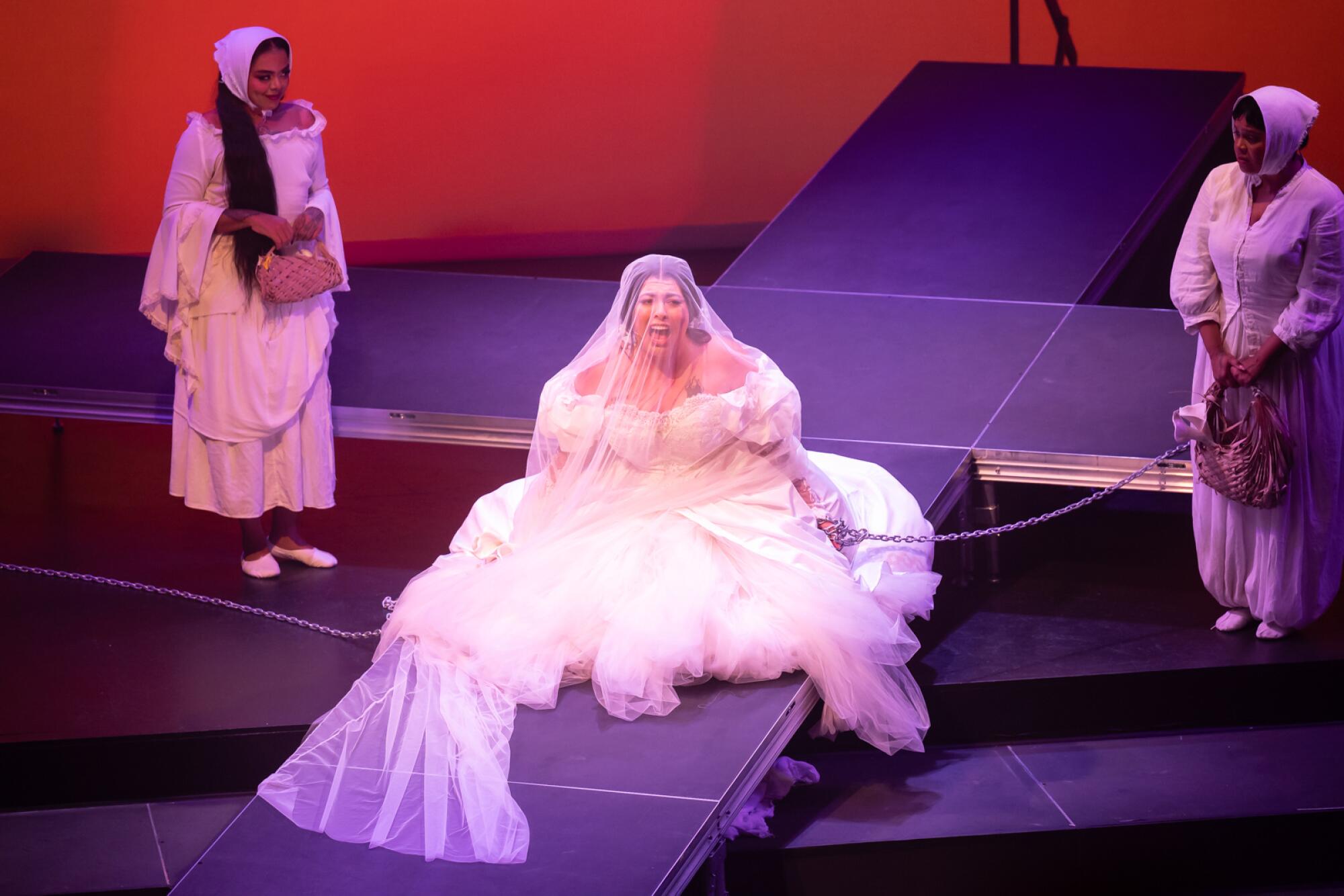 San Cha sits on the floor with one hand in chains during a performance of her opera “Inebria me”