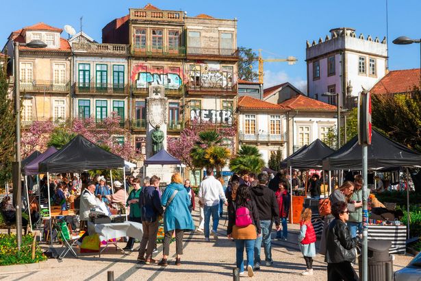 Porto, Portugal - 1 March, 2025: tourists and locals browse the stalls selling souvenirs and traditional Portuguese wares at an outdoor street market in the old town of Porto, Portugal.