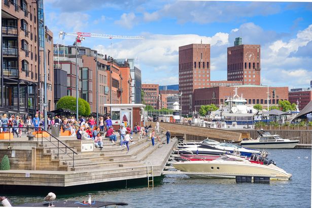 Oslo, Norway – July 17, 2017: The City Hall of Oslo, People enjoying the summer at Aker Brygge, the popular leisure district on the Oslo waterfront overlooking the marinas of Oslofjrden, Norway.
