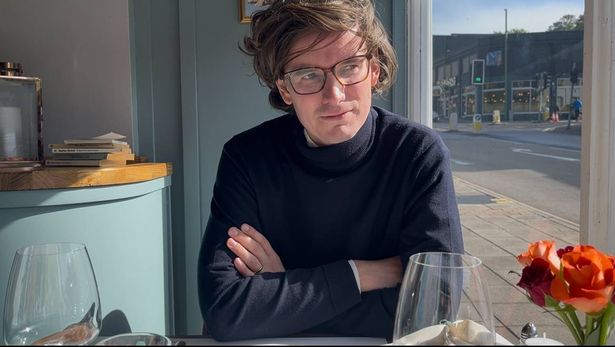 Milo Boyd sits in a restaurant in Torquay looking thoughtfully out of the window