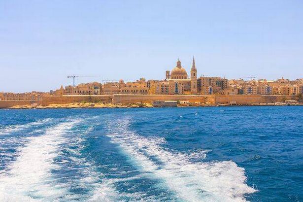 Water trail behind a passing boat with Valetta city view