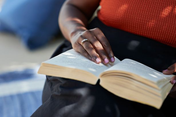 Midsection of mature woman wearing ring while sitting with book