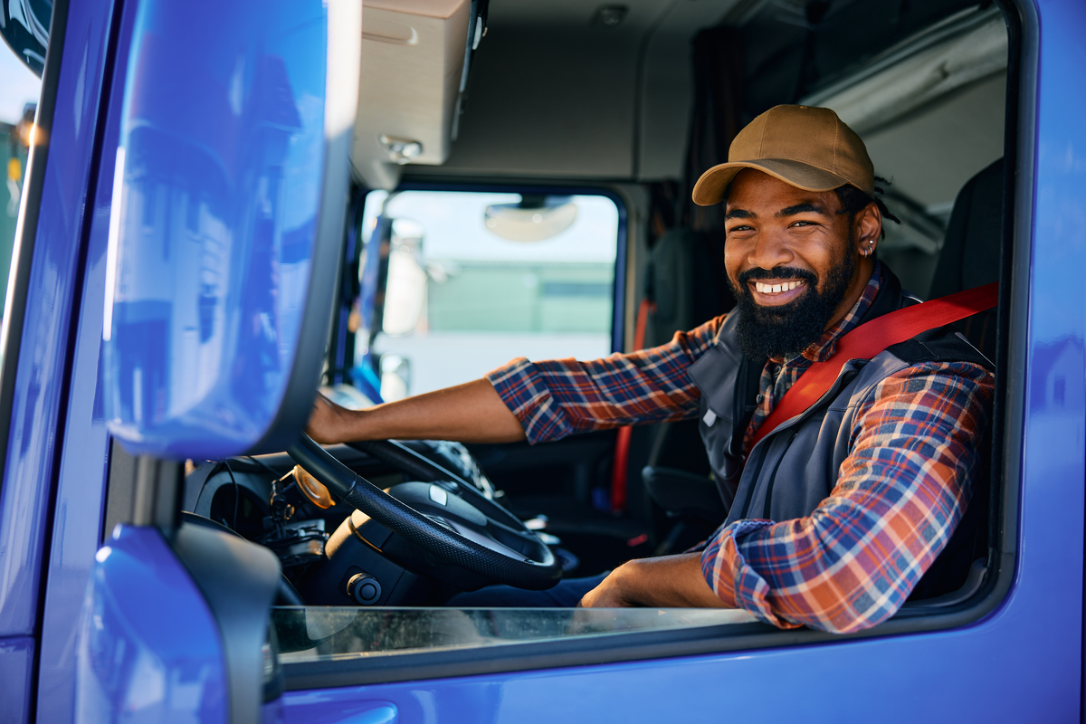 A trucker sits in the cab of his truck.
