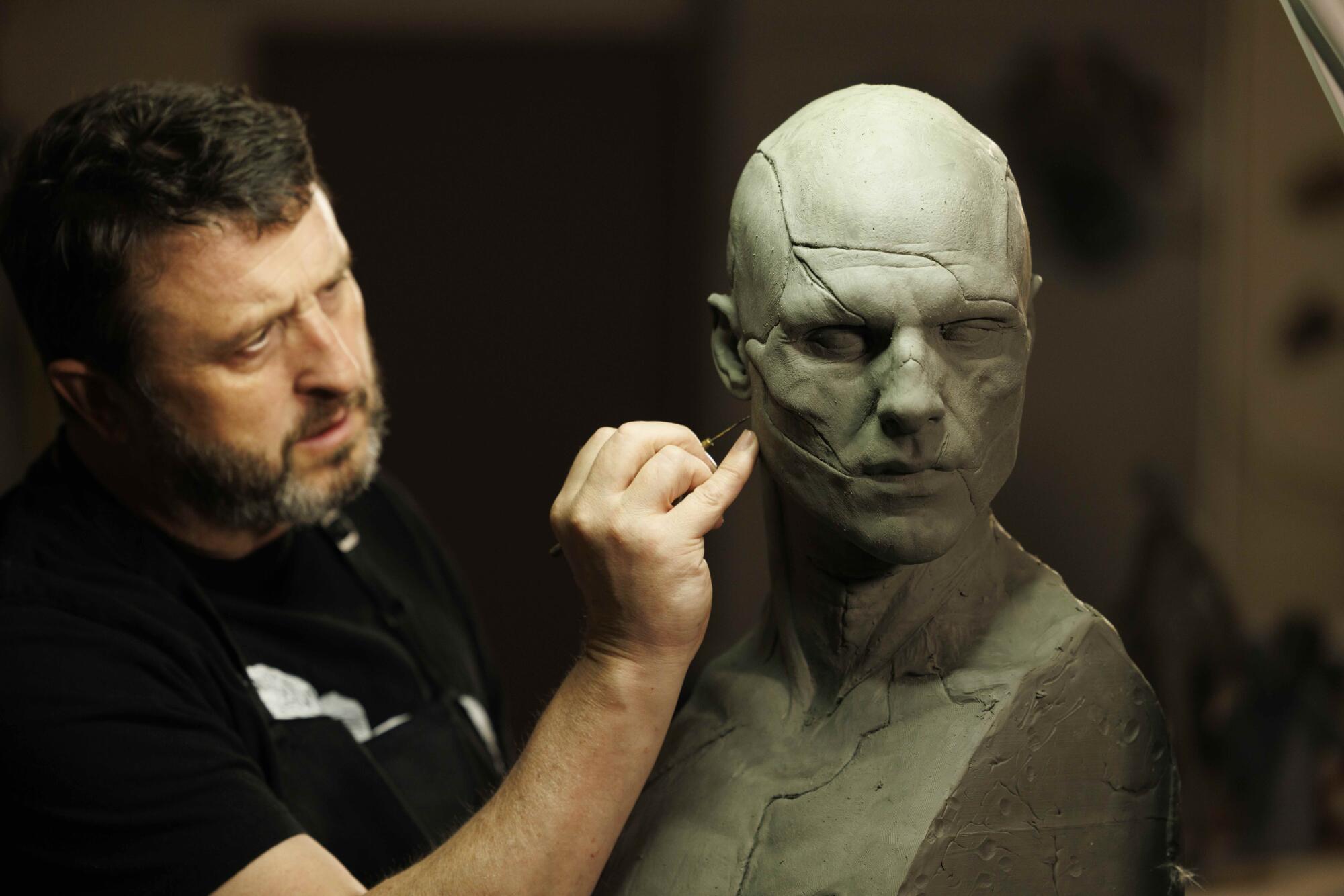 A prosthetics designer works on a model for a creature.