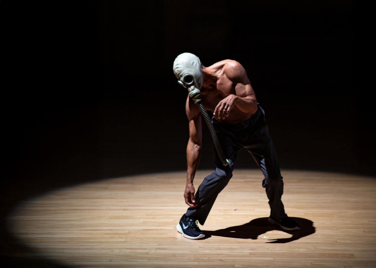 A shirtless man wearing a gas mask dancing.
