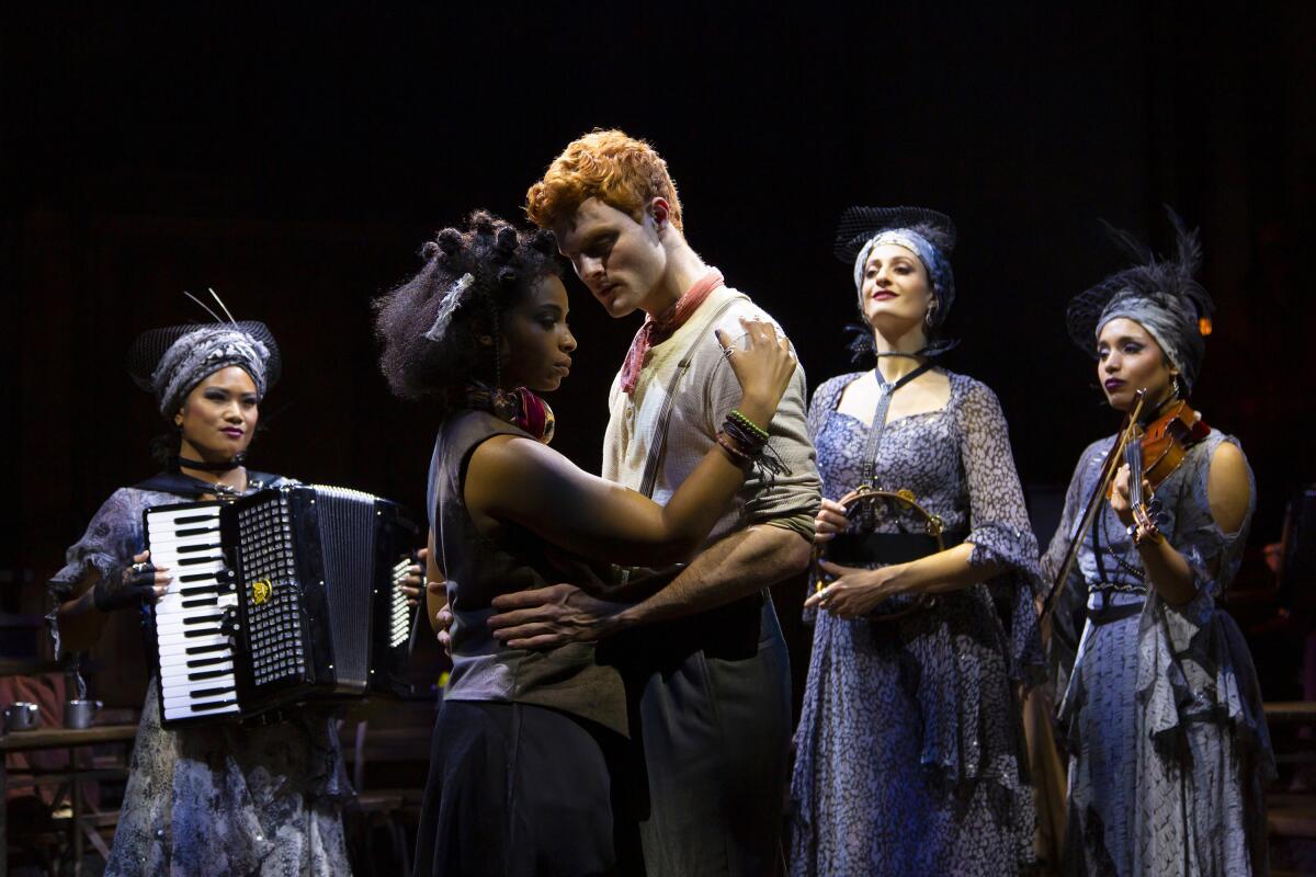 Two actors slow dance as an accordionist and a violinist look on.