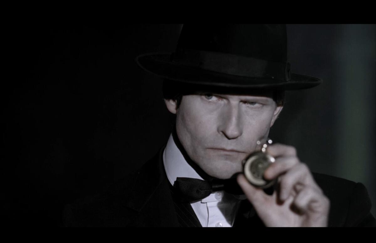 A man in a suit holds a stopwatch.