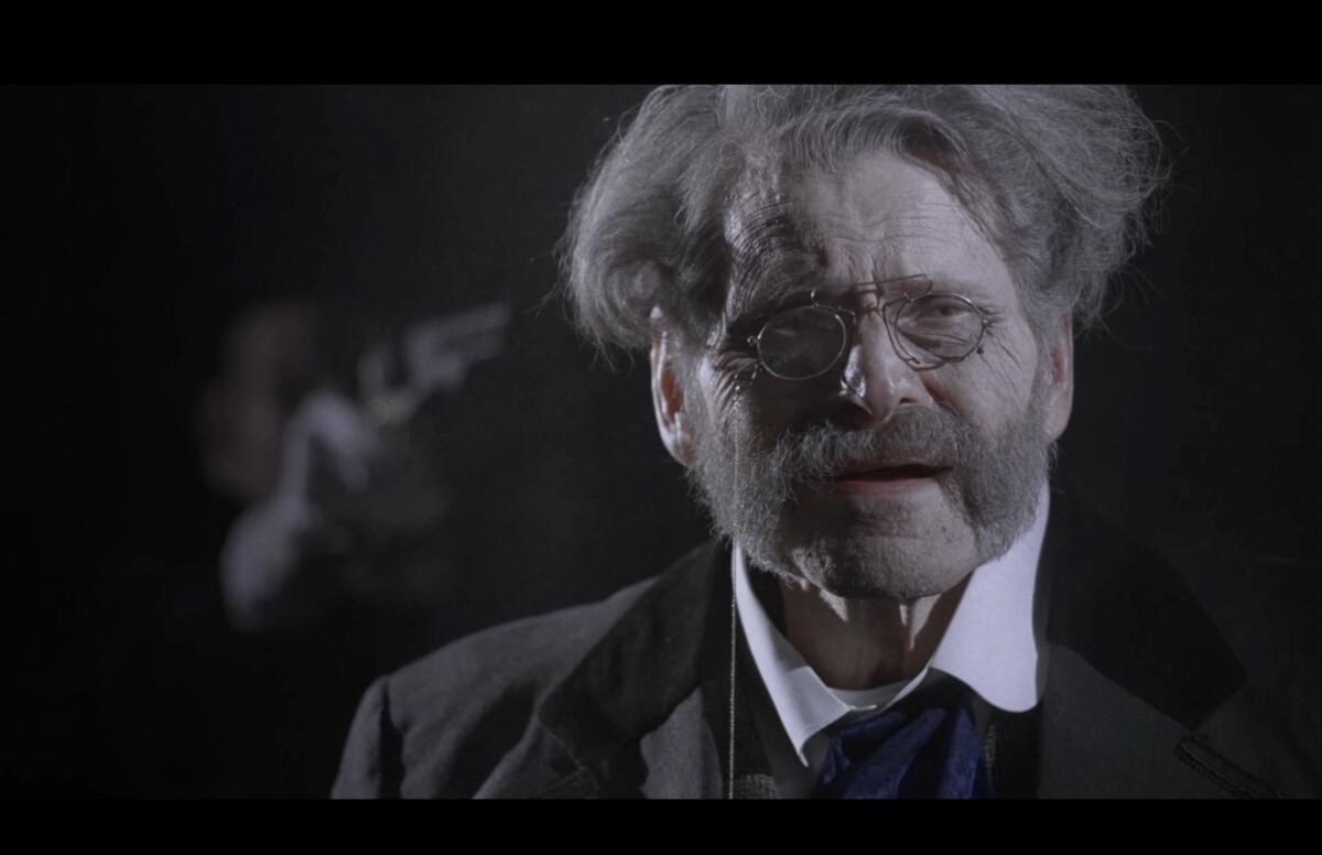 A man with a walrus mustache speaks to the lens.