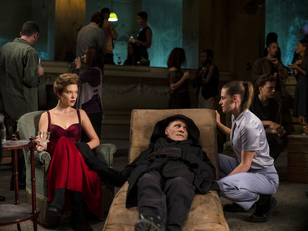 Two women sit next to a reclining man in black.