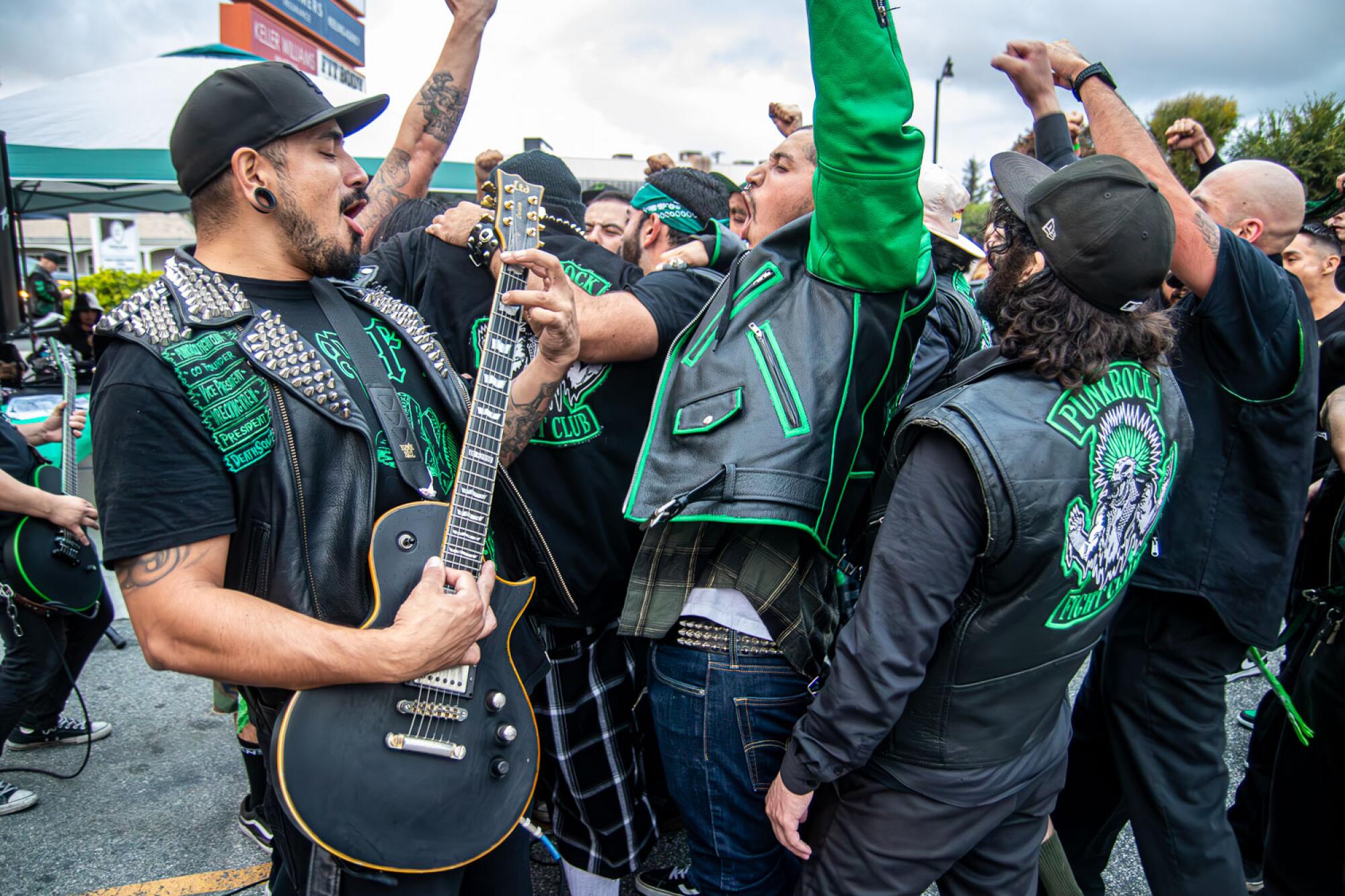 Group of punks performing in a parking lot in leather jackets.