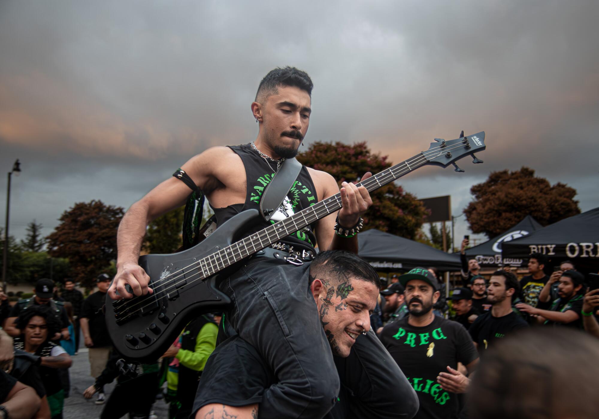 The bassist known as Knucklehead Randy performs while riding on the shoulders of a fellow club member