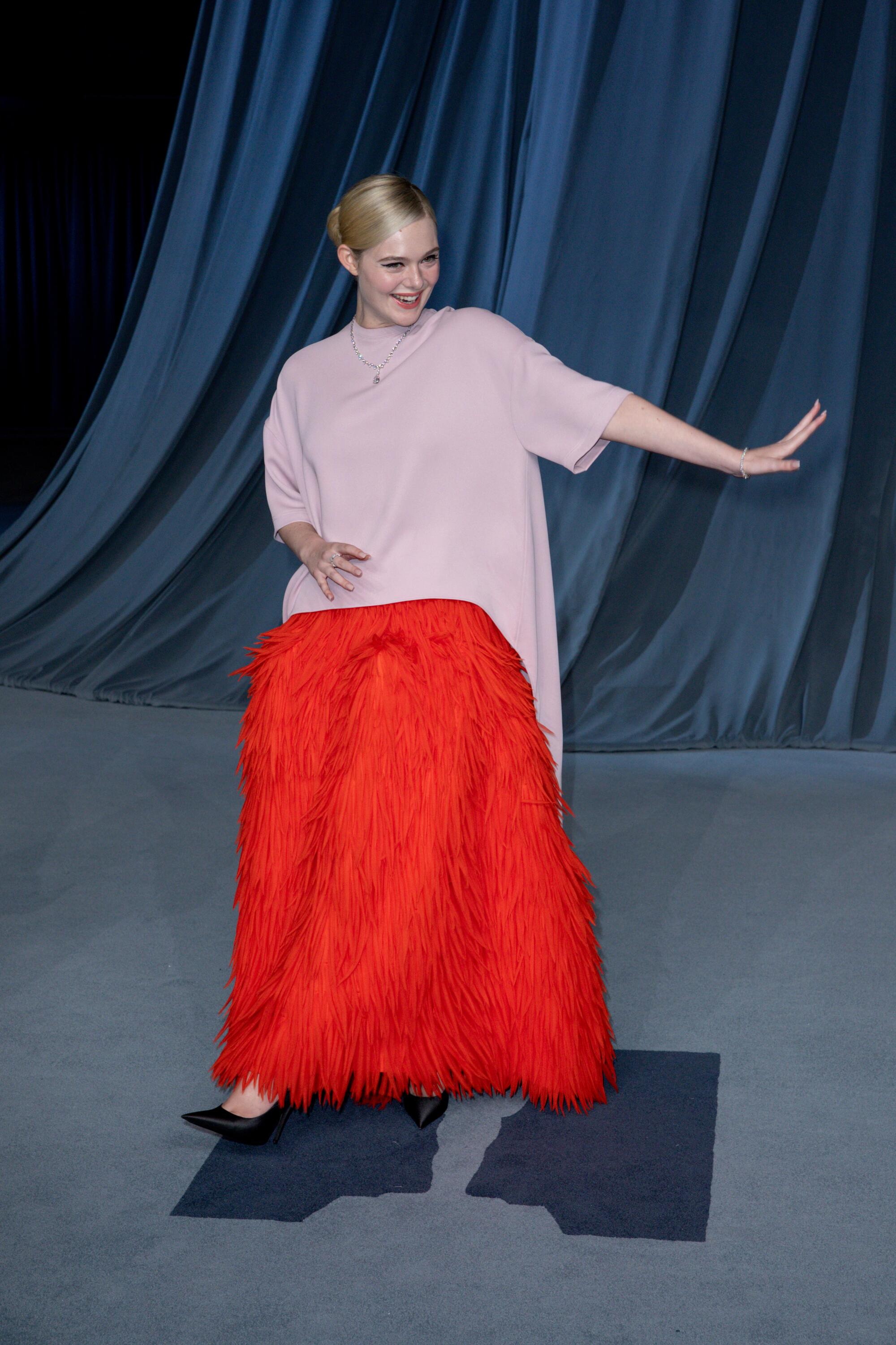 Elle Fanning wears a gown with a red feathered skit.