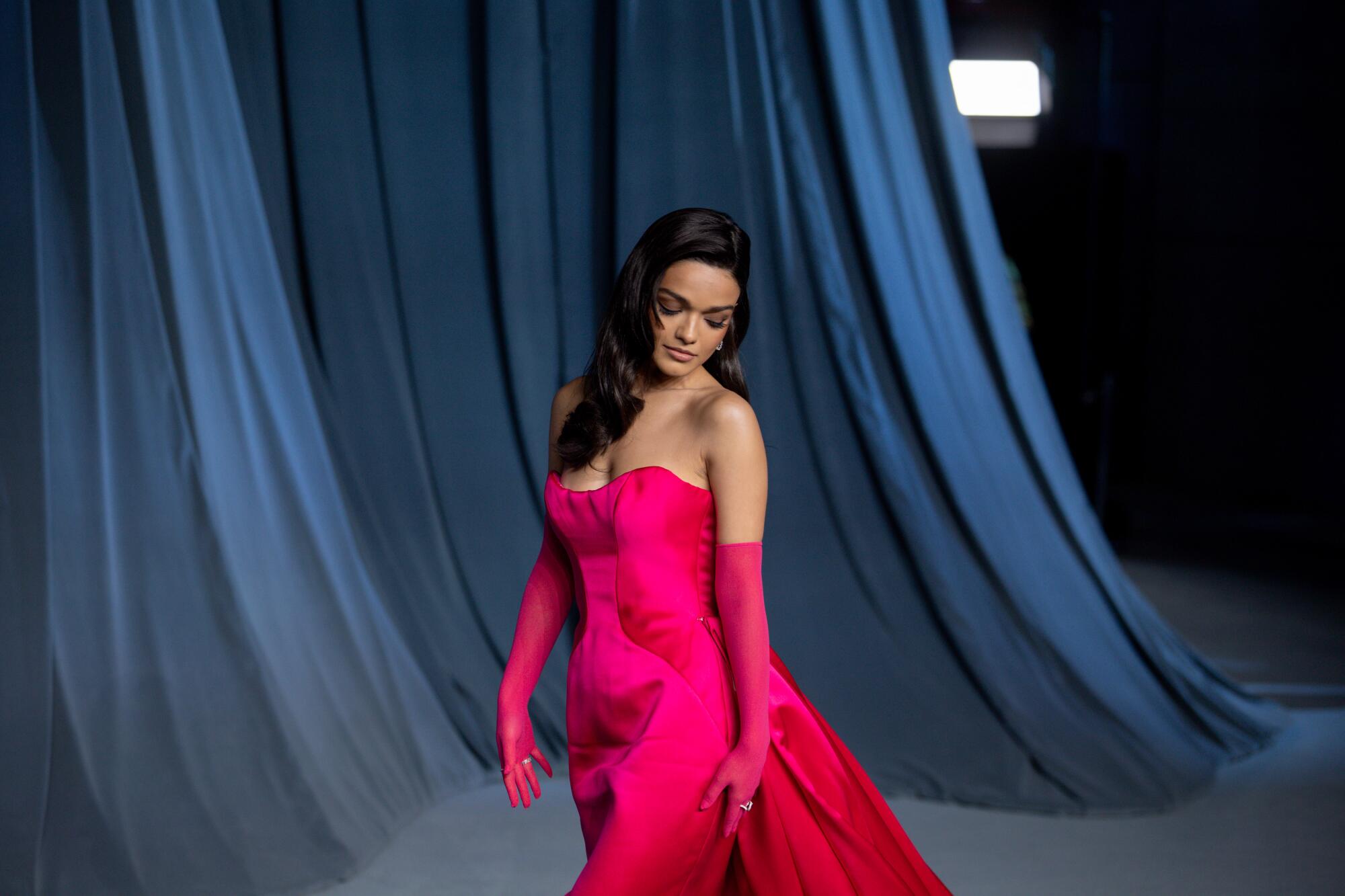 Rachel Zegler wears a fuchsia gown with matching gloves.