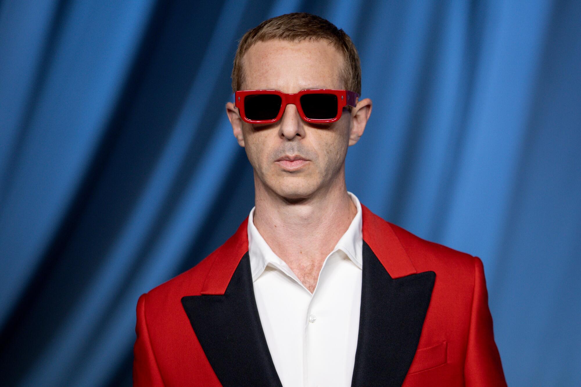Jeremy Strong wears a red suit jacket and sunglasses.