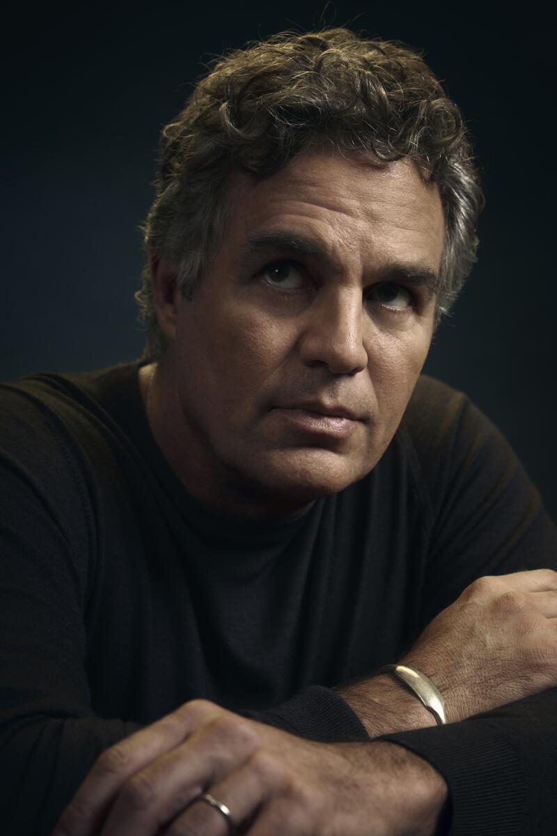 A man in a sweater gazes into the distance.