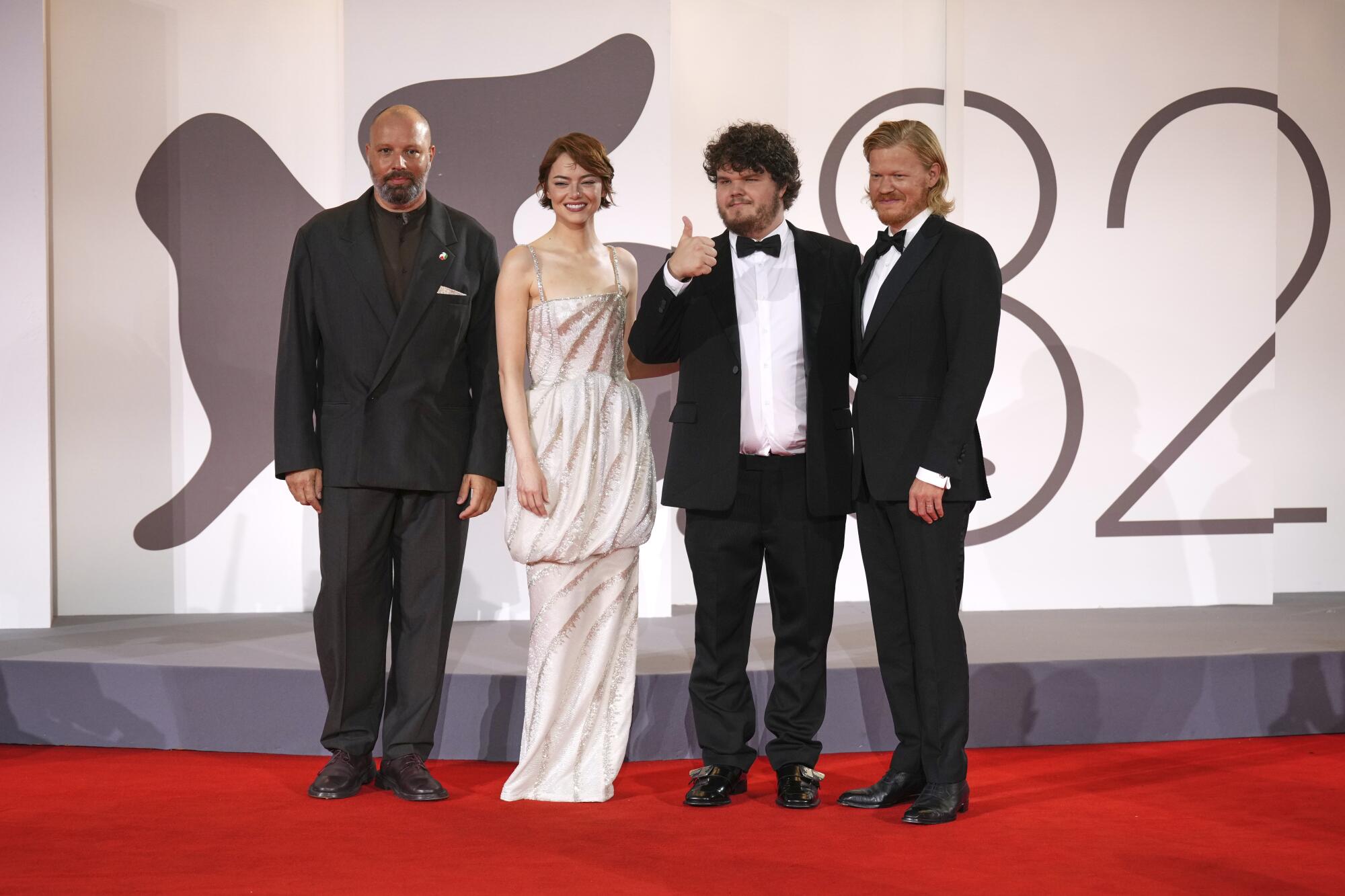 Four people smile on a red carpet at a film festival.