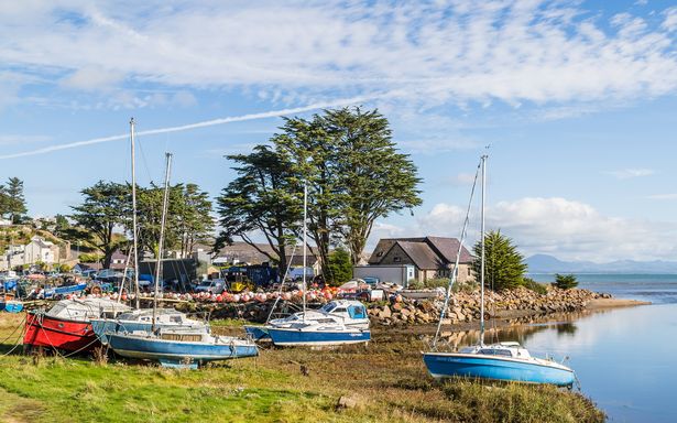 Various coloured fishing boats on the sides of the River Soch at low tide at Abersoch on the North Wales coastline.