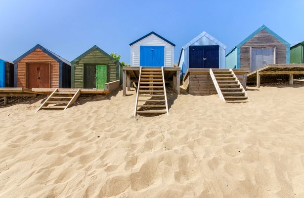 A line of beach huts on a sandy beach