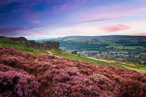 Sunset over the village of Ilkley and a hill of purple heather