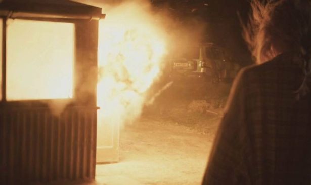 The back of a woman standing in front of a burning building