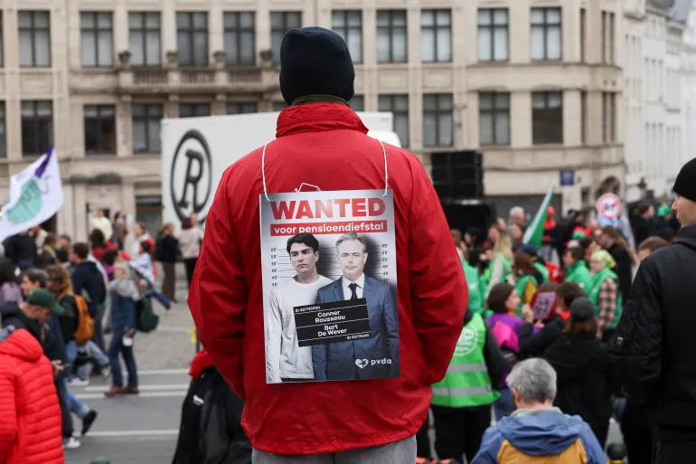 A protester with a sign depicting Belgian Prime Minister Bart De Wever and politician Conner Rousseau that reads "Wanted for pension theft" attends a demonstration during a nationwide strike against the Belgian government's reform plans, in Brussels, Belgium, October 14, 2025. REUTERS/Omar Havana