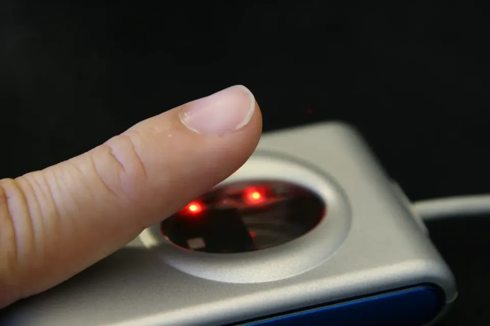 A person placing their thumb on a fingerprint scanner.