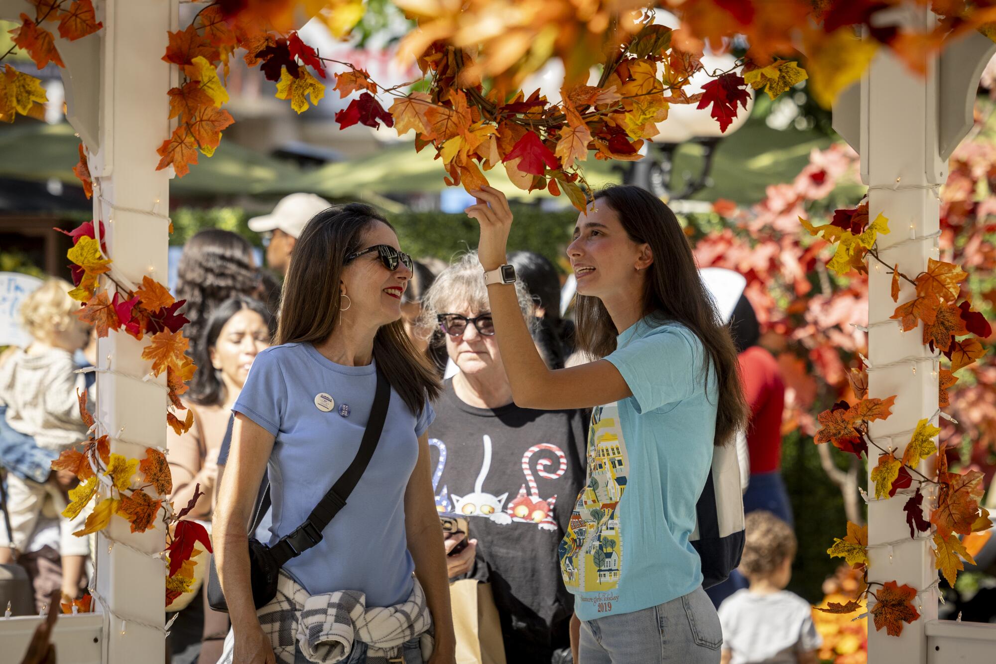 A photo of two women in a gazebo with fall decor strung up on the structure.