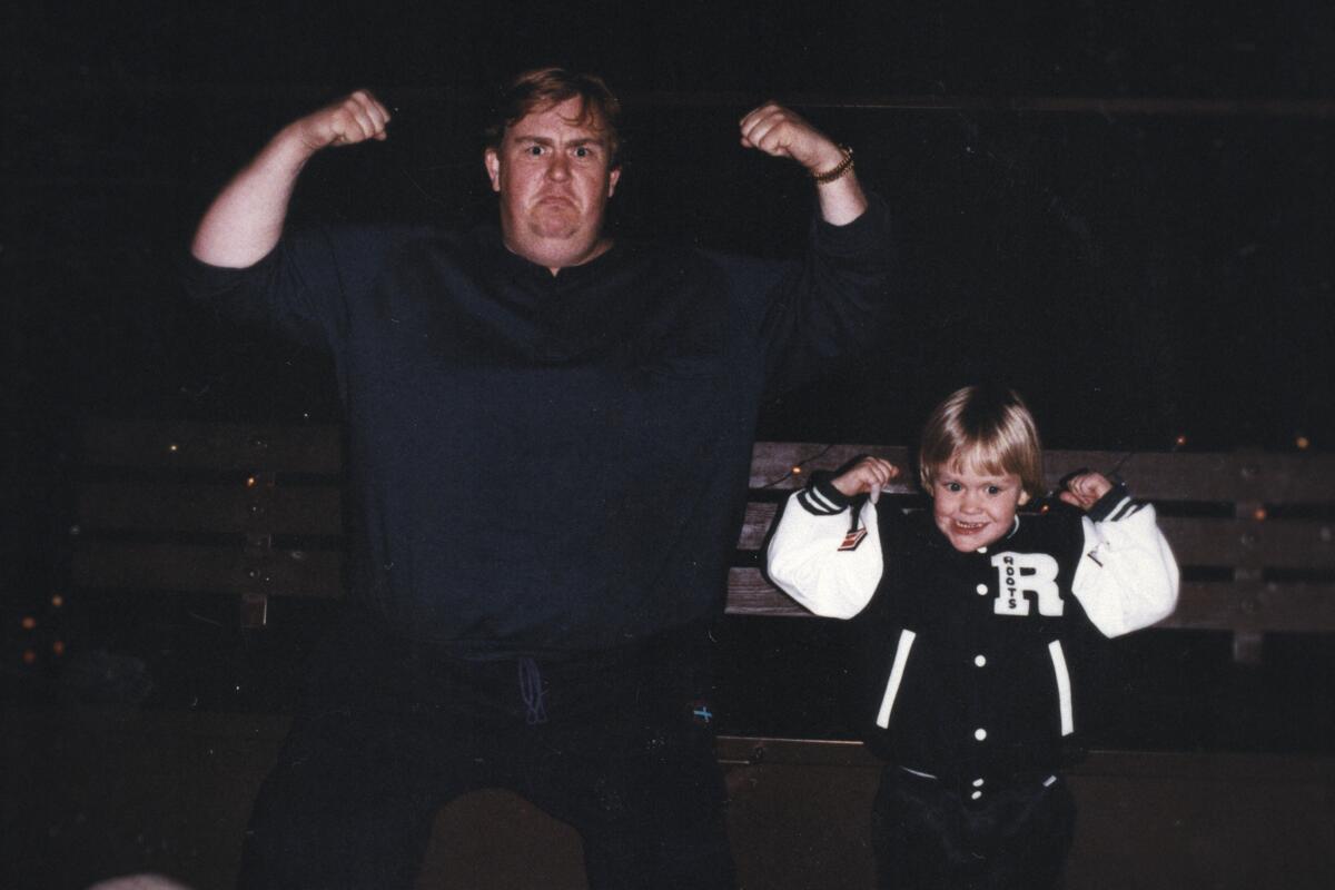 A man and a little boy with their arms raised.