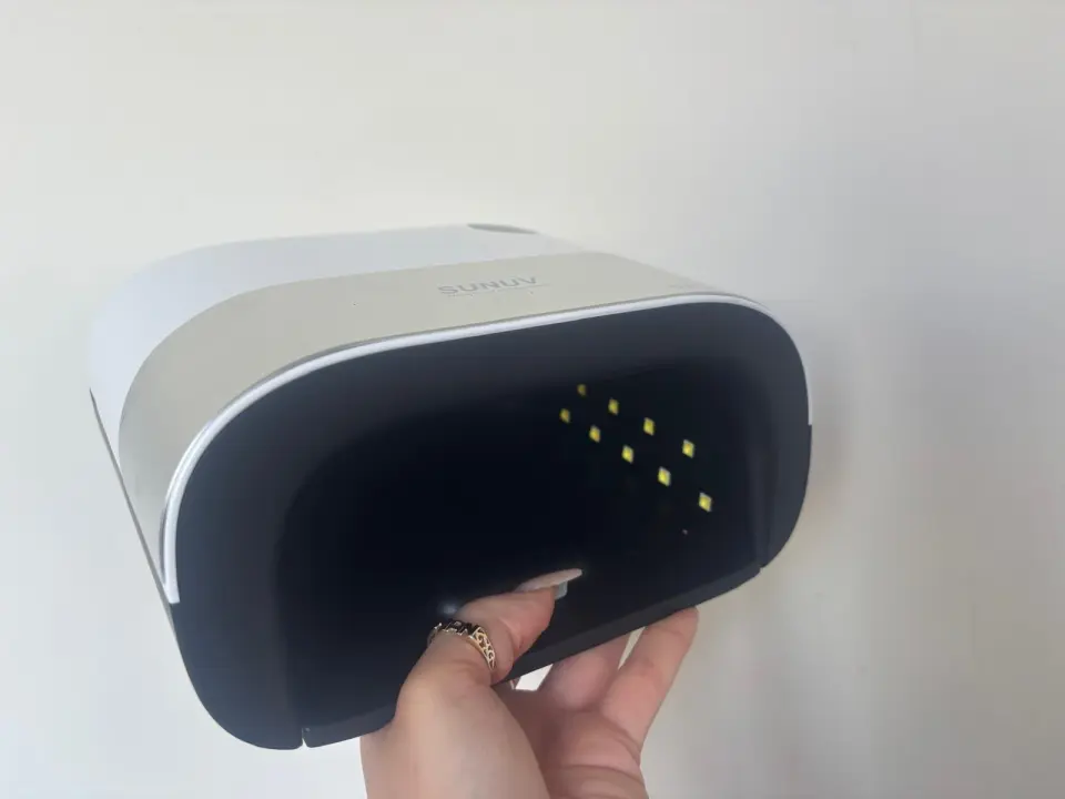 Hand holding open a SUNUV LED nail lamp.
