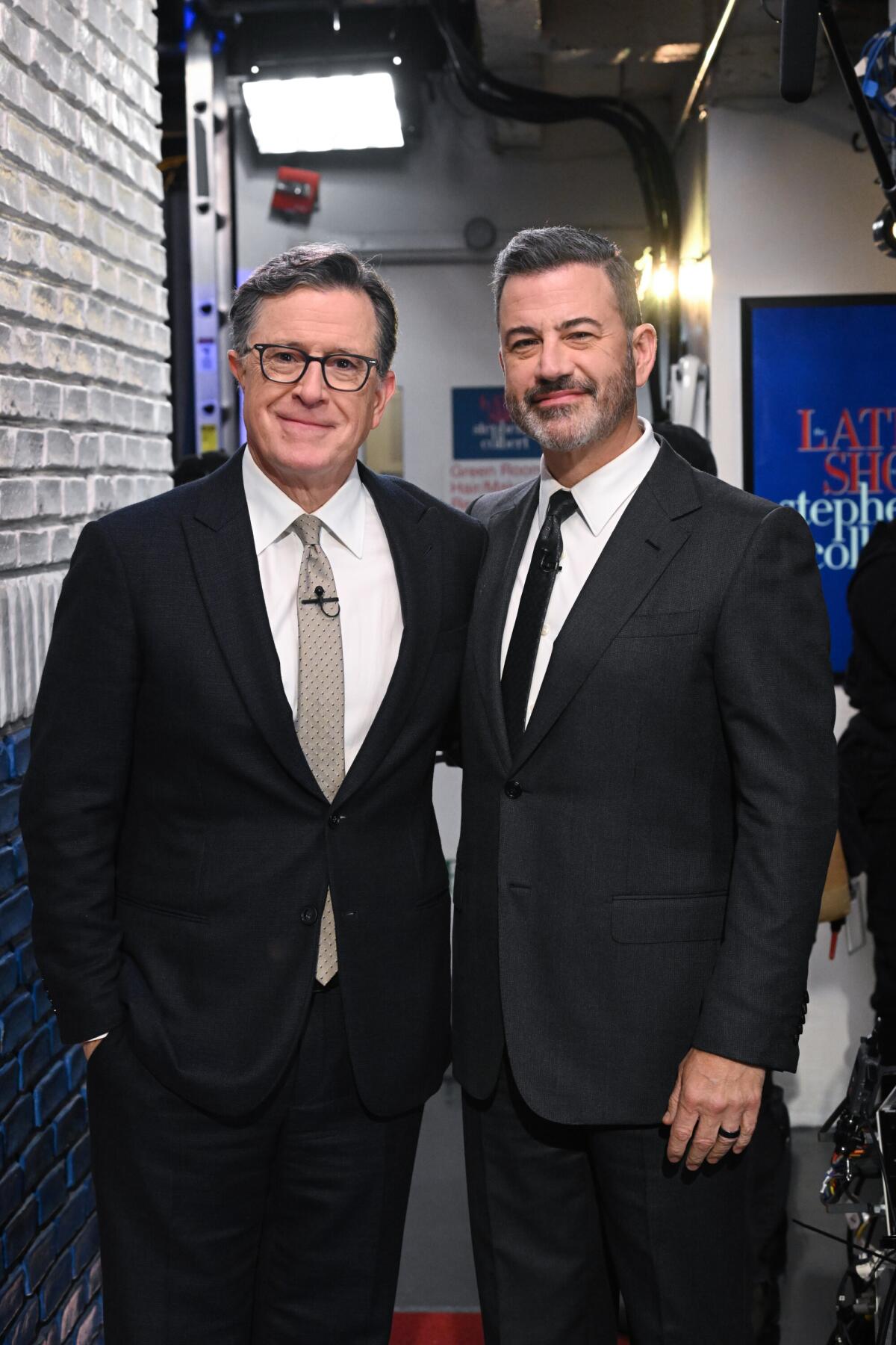 Two men in suits standing side by side backstage.