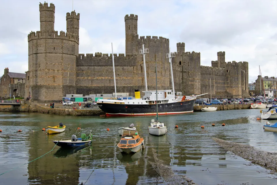 Caernarfon Castle with a large boat docked in the harbor.
