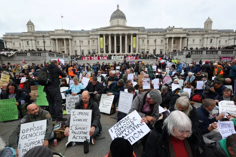Protesters hold signs, during a mass demonstration organised by Defend our Juries, against the British government's ban on Palestine Action, at Trafalgar Square in London, Britain, October 4, 2025. REUTERS/Toby Melville