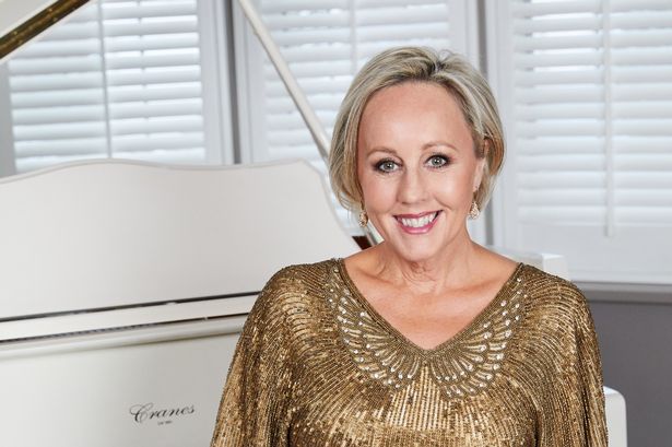 Shirlie Kemp wears gold sequins as she sits at her piano