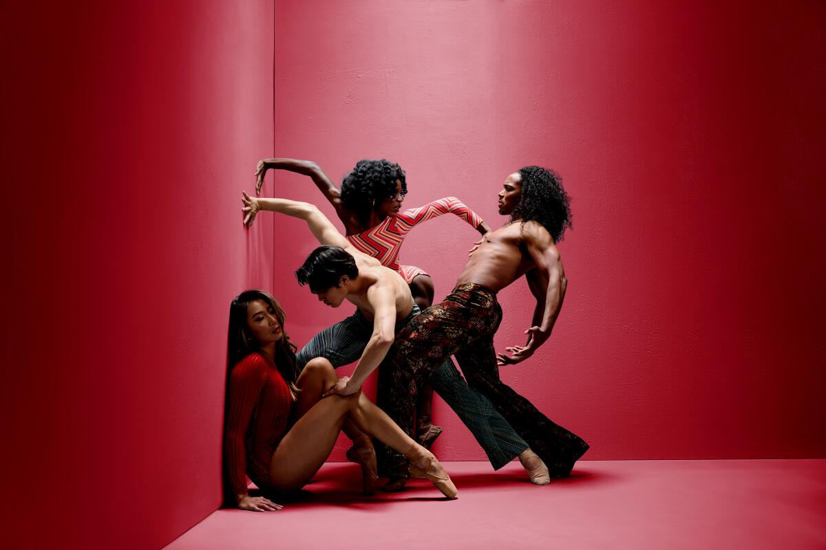Four dancers perform in a red-walled corner.